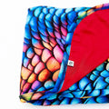 Colorful dragon scale patterned fabric with a red interior on a white background