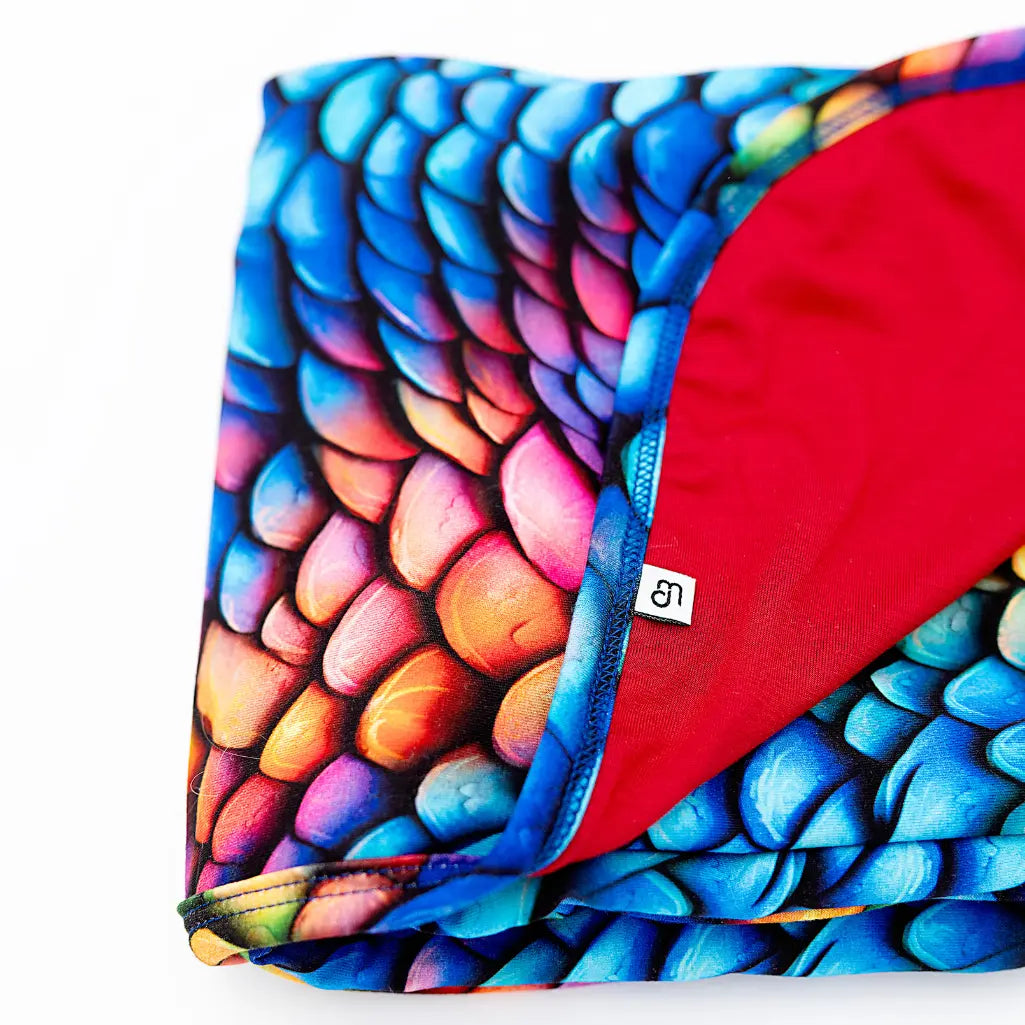 Colorful dragon scale patterned fabric with a red interior on a white background