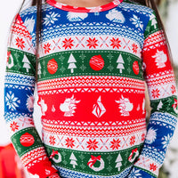 Close up of the chest and sleeves of a long sleeve pajama top in red, green, blue, and white fair isle stripes with snowflakes, pine trees, and white dragon heads.