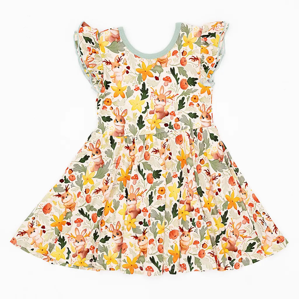 A flutter sleeve twirl dress with sage green trim laid flat on a white background in a woodland antlered bunny print.