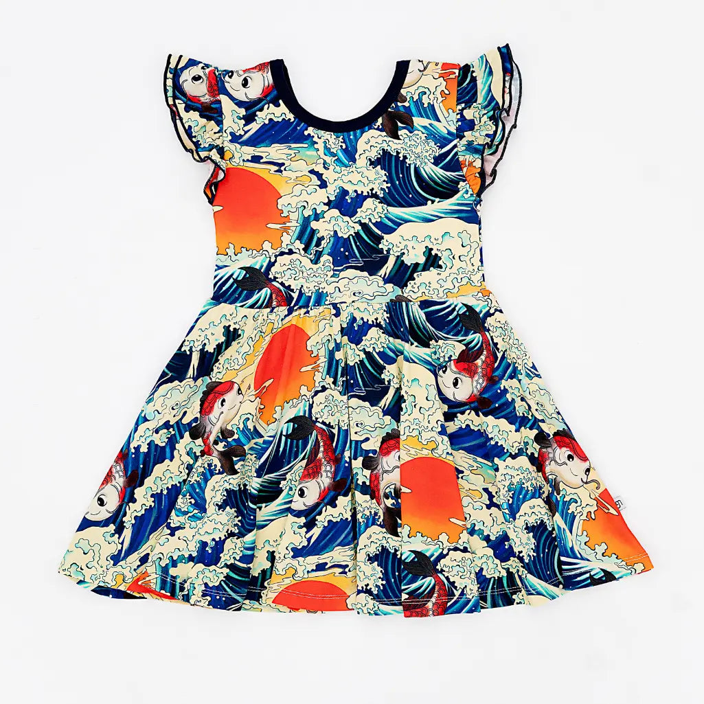 Flat lay of a flutter sleeve twirl dress with navy trim in a koi fish, ocean wave, and sunset print on a white background.