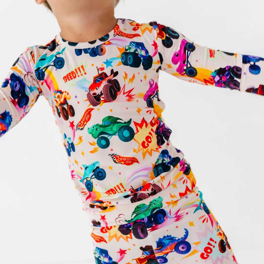Close-up of a child in motion wearing a cream pajama set with a colorful monster truck print and words like Speed and Go.