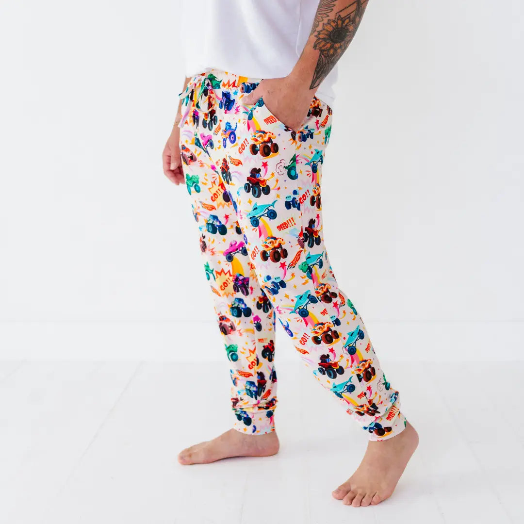 Side view of men's pajama pants with a colorful monster truck print and cuffed ankles.