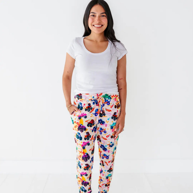 A mother in a white tee wearing women's pajama pants with a colorful monster truck print.