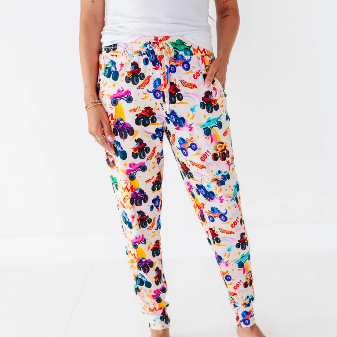 Front view of women's jogger-style pajama pants with a colorful monster truck print and drawstring waist.
