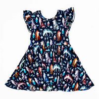 Flat lay of a flutter sleeve twirl dress in a navy print of geometric wolves, triangle pine trees, and snowflakes on a white background.