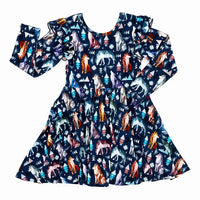 Flat lay of a long sleeve twirl dress with flutter ruffles at the shoulders in a navy print of geometric wolves, triangle pine trees, and snowflakes on a white background.