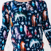 Close up of the front of a long sleeve pajama top with a round collar in a navy print of geometric wolves, triangle pine trees, and snowflakes.