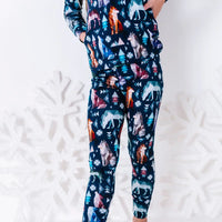 Close up of the matching pants and the hem of a long sleeve pajama top in a navy print of geometric wolves, triangle pine trees, and snowflakes.