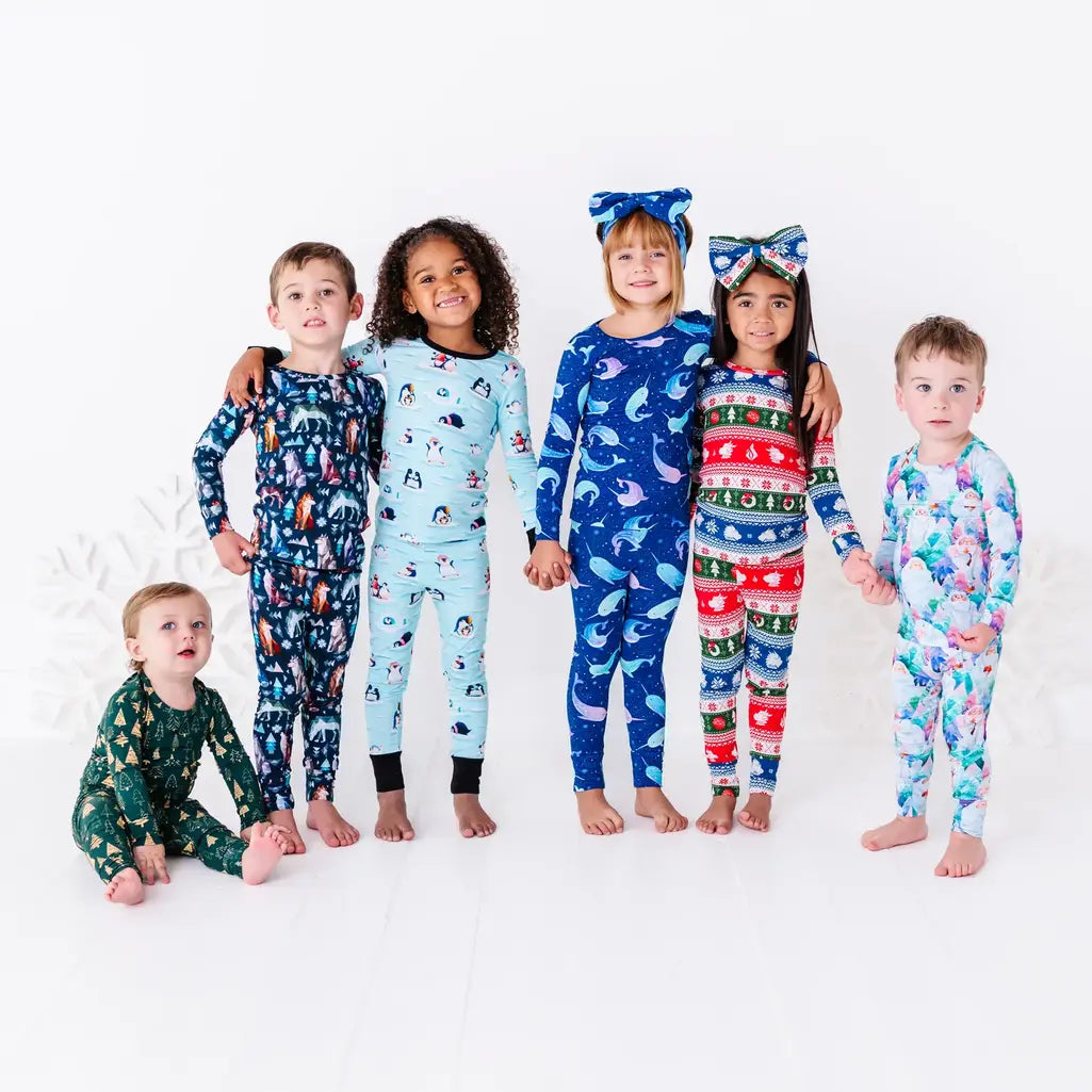 Five kids standing in a row in matching holiday pajama sets in six different winter prints, with a baby sitting beside them.