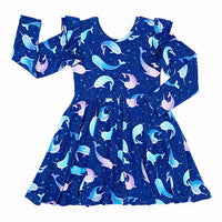 Flat lay of a long sleeve twirl dress with flutter ruffles at the shoulders in a royal blue print of blue and lavender narwhals on a white background.