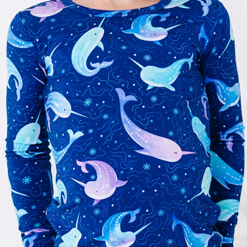 Close up of the front of a long sleeve pajama top in a royal blue print of blue and lavender narwhals.