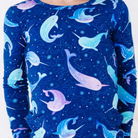 Close up of the front of a long sleeve pajama top in a royal blue print of blue and lavender narwhals.