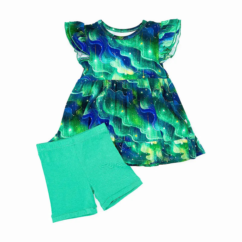 Flat lay of a flutter sleeve peplum top in a green and blue northern lights print with mint green bike shorts on a white background.