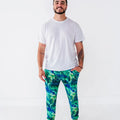 A man in a white tee wearing jogger pajama pants with a green and blue northern lights pattern with stars.