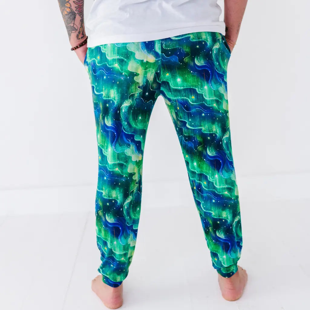 Back view of jogger pajama pants with a swirling green and blue northern lights pattern dotted with stars.