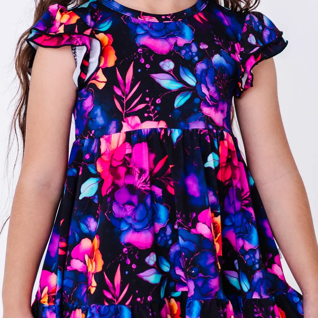 Close up of the front of a flutter sleeve peplum top in a black watercolor floral print.