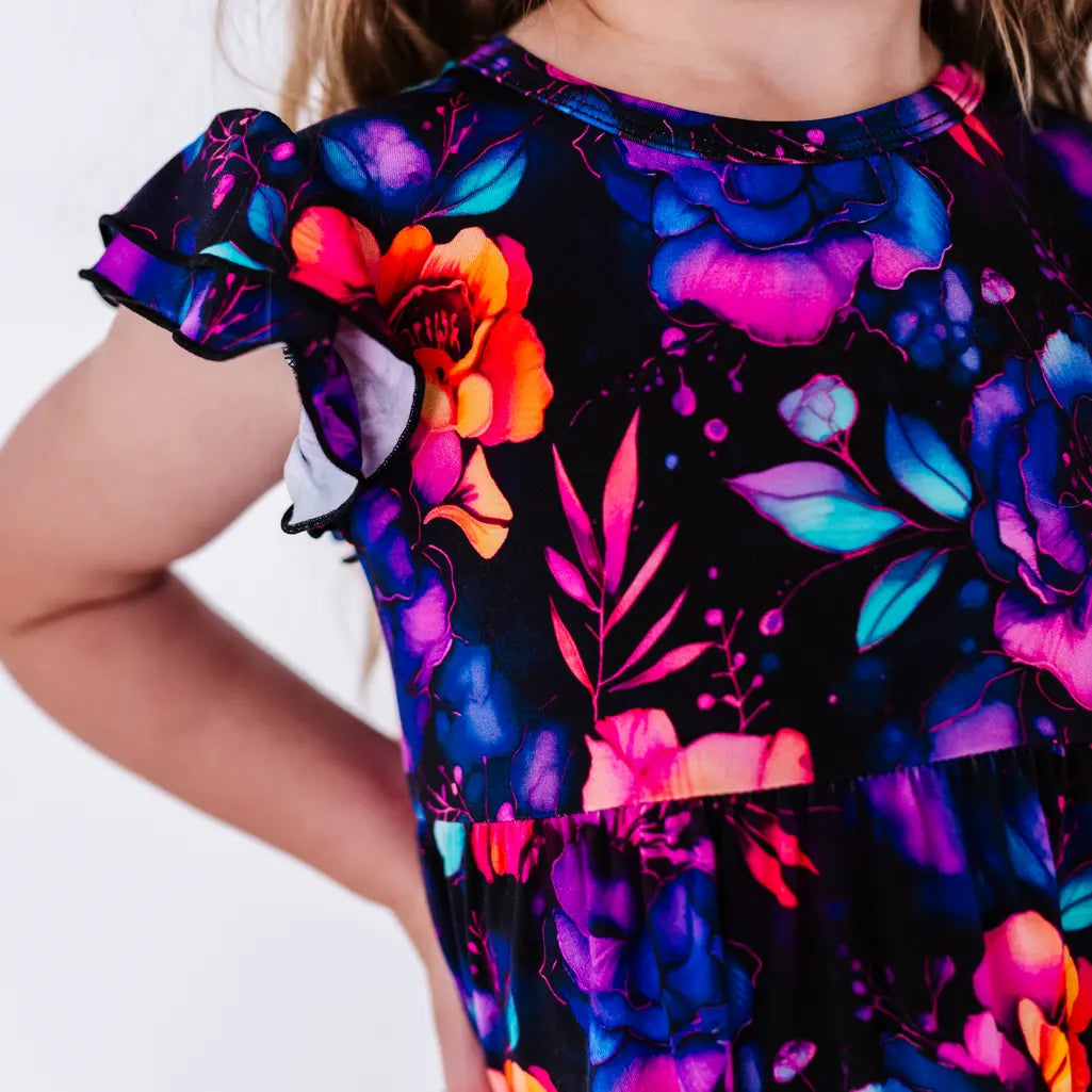 Close up of a ruffled sleeve and the bodice of a flutter sleeve peplum top in a black watercolor floral print.