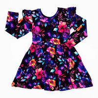 Flat lay of a long sleeve twirl dress with flutter ruffles at the shoulders in a black print of pink, orange, purple, and blue watercolor flowers on a white background.