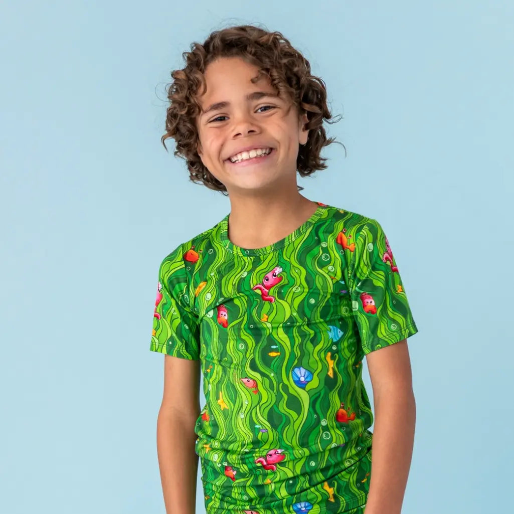 Child wearing a green patterned shirt against a light blue background