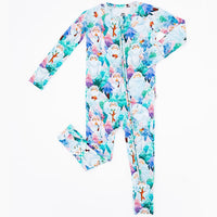 Flat lay of a zip up convertible baby pajama in a print of friendly white yetis among teal, blue, and purple pine trees on a white background.